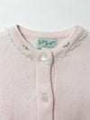 Carriage Boutique pink cotton cardigan featuring delicate lace trim and embroidered rosebud details at the crew neck.