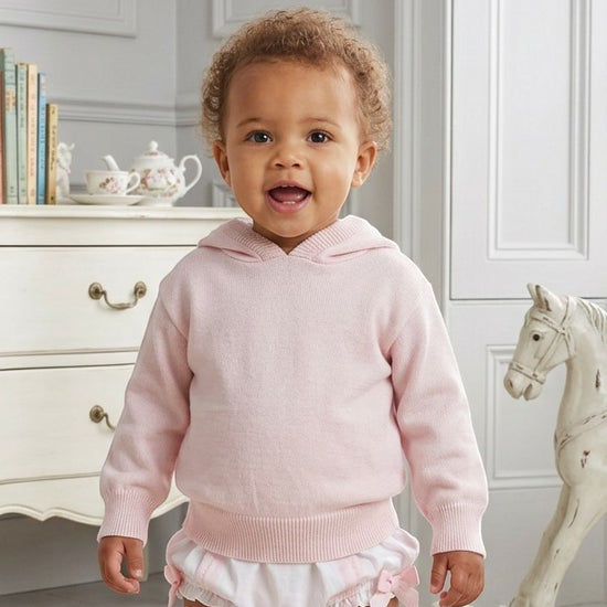 Carriage Boutique baby girl wearing a soft pastel pink cotton knit hooded sweater with ribbed trim.