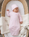 Carriage Boutique pink newborn sleep sack with matching hat and personalized name embroidery in a wicker bassinet.