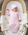 Carriage Boutique pink newborn sleep sack with matching hat and scalloped trim, worn by a sleeping baby in a basket.
