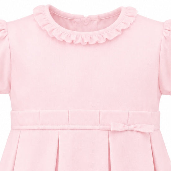 Carriage Boutique pink pique baby girl dress with a ruffled collar, pleated skirt, and delicate waist bow detail.
