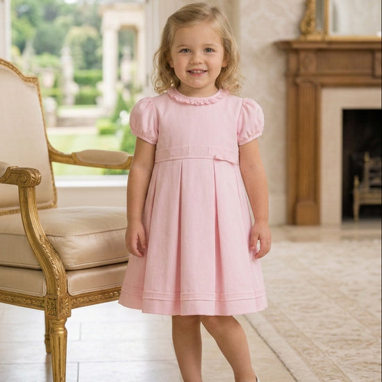 Carriage Boutique pink pique toddler girl dress with puff sleeves and pleated skirt worn by a young girl