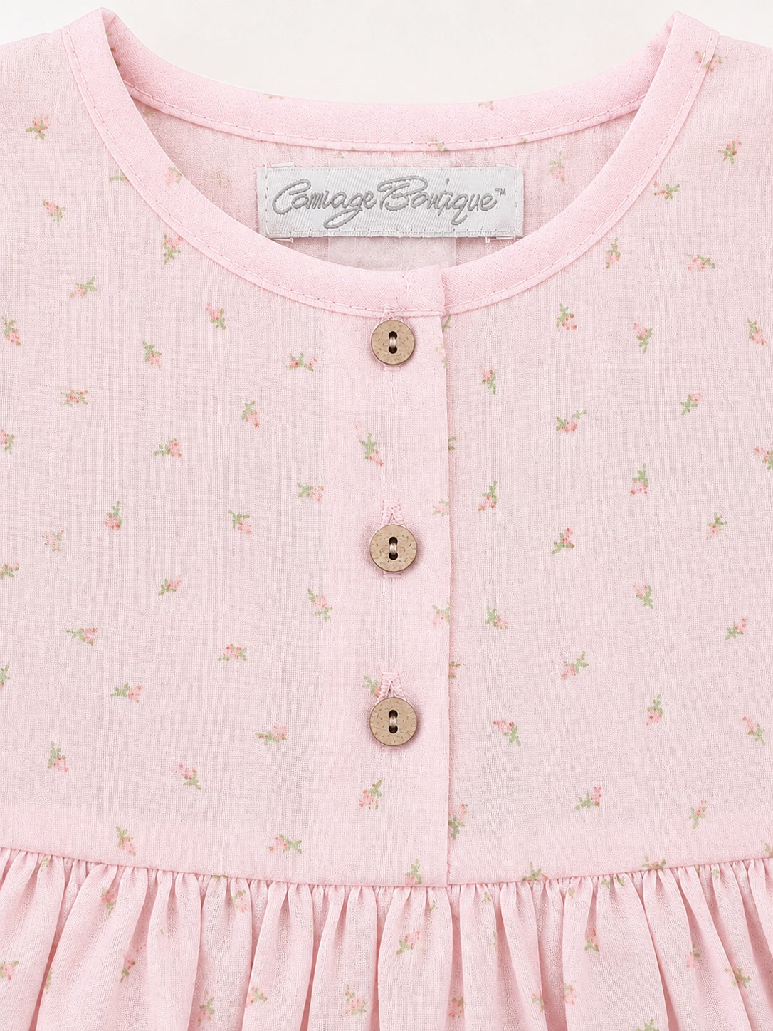 Carriage Boutique baby girl dress in soft pink with a delicate rosebud print, featuring wooden buttons and a round neck