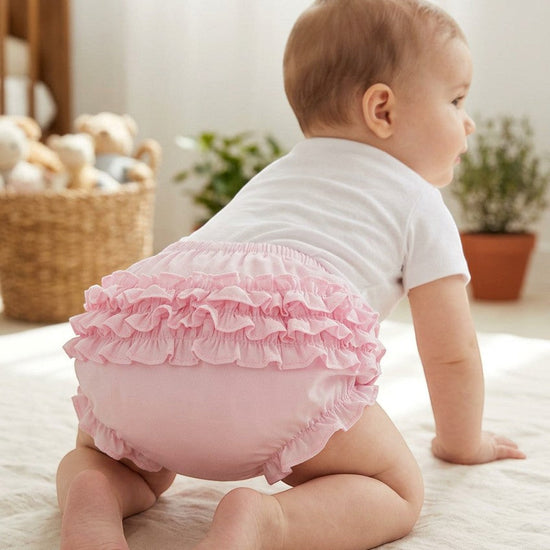 Carriage Boutique baby girl wearing pink ruffled diaper cover bloomers with an elastic waistband while crawling.