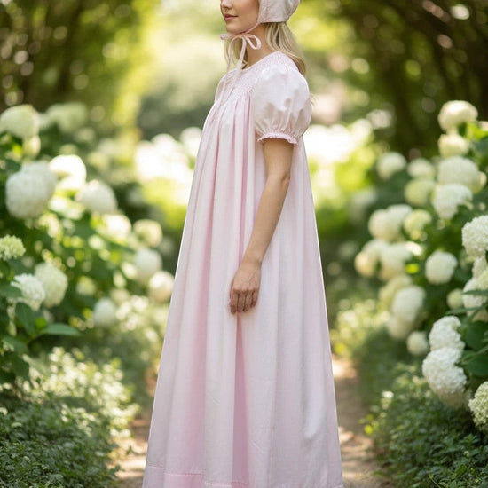 Carriage Boutique pink hand-smocked bishop dress with pearl cross detail and matching bonnet. 100% cotton.