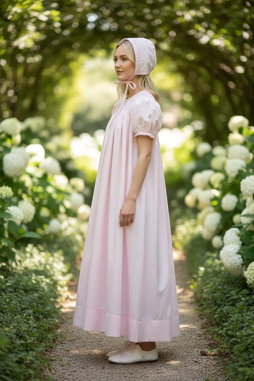 Carriage Boutique pink hand-smocked bishop dress with pearl cross detail and matching bonnet. 100% cotton.