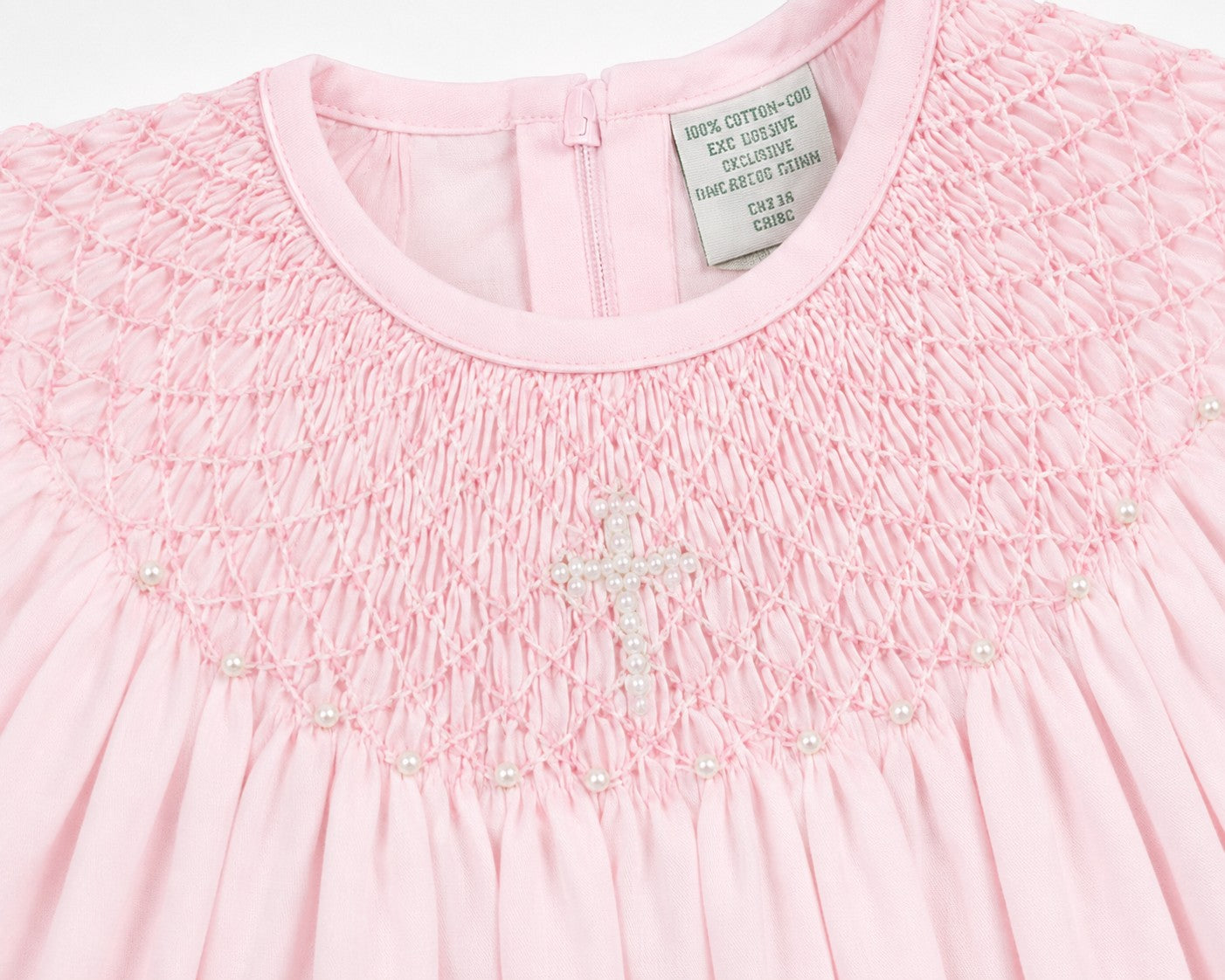 Carriage Boutique pink cotton baby christening bishop dress with hand-smocked detail and pearl cross embellishment.