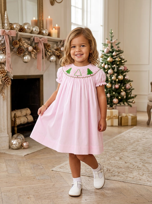 Toddler girl wearing a Carriage Boutique pink cotton bishop dress with hand-smocked Christmas tree embroidery.