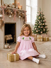 Carriage Boutique toddler girl wearing a light pink cotton bishop dress with hand-smocked green Christmas tree details.