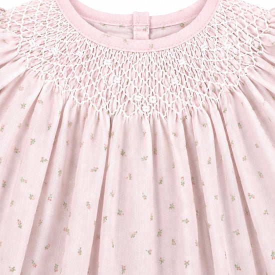 Carriage Boutique pink cotton baby dress featuring delicate rosebud print and intricate white hand-smocked detailing.