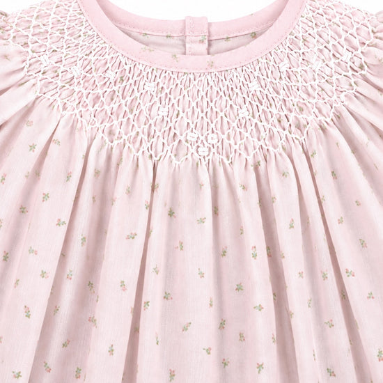 Carriage Boutique pink cotton baby dress featuring delicate rosebud print and intricate white hand-smocked neckline.