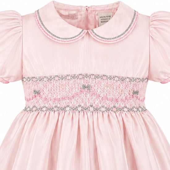 Carriage Boutique pink taffeta toddler dress featuring hand smocked detailing, a peter pan collar, and short sleeves.