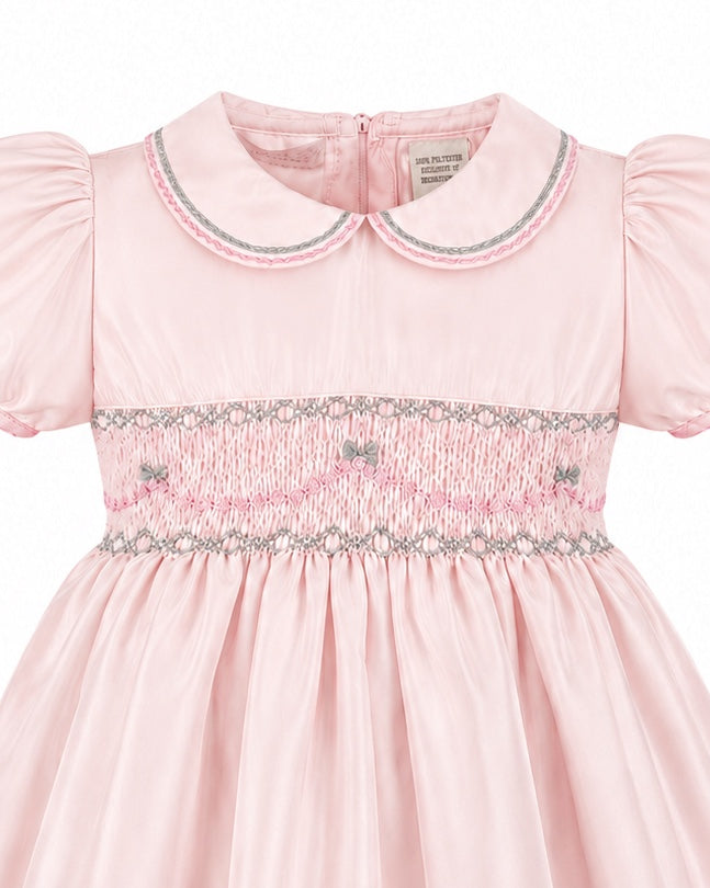 Carriage Boutique pink taffeta toddler dress featuring hand smocked detailing, a peter pan collar, and short sleeves.