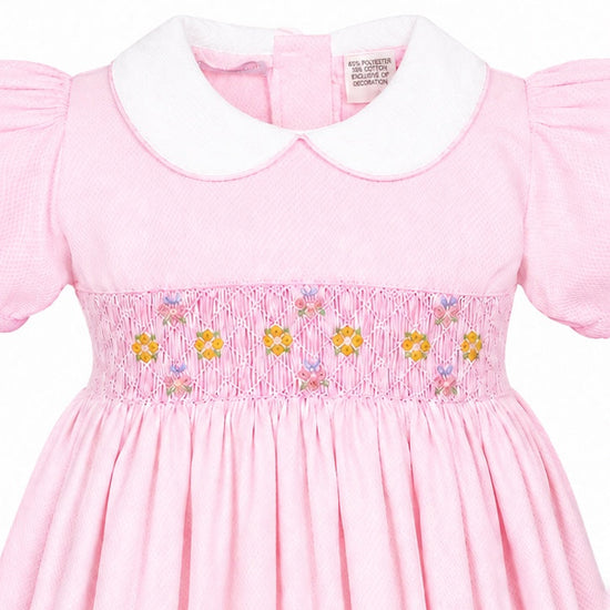 Carriage Boutique pink toddler dress with white collar, short sleeves, and delicate smocked yellow flower embroidery.