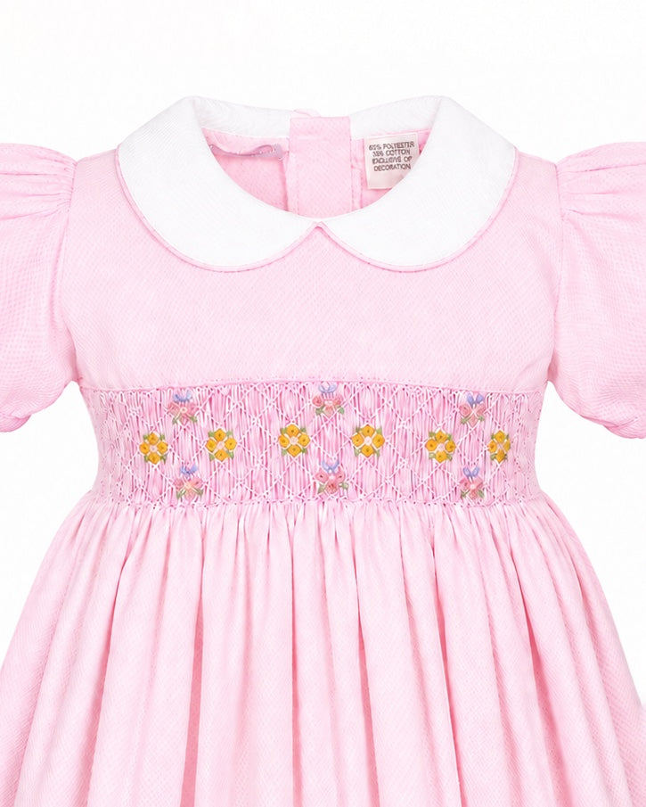 Carriage Boutique pink toddler dress with white collar, short sleeves, and delicate smocked yellow flower embroidery.