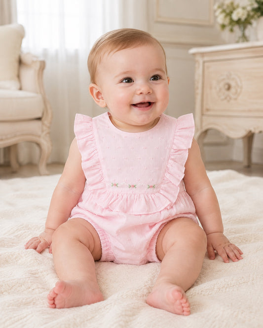 Carriage Boutique baby girl bubble romper in soft pink Swiss dot fabric with ruffled shoulders and floral embroidery.