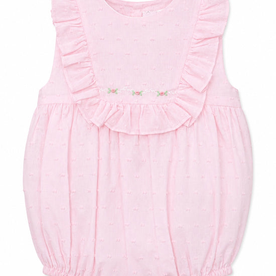 Carriage Boutique baby girl bubble romper in soft pink with Swiss dot texture, ruffled shoulders, and floral detail.