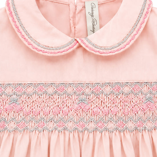 Carriage Boutique pink taffeta baby girl dress with a peter pan collar and intricate hand-smocked floral detailing.