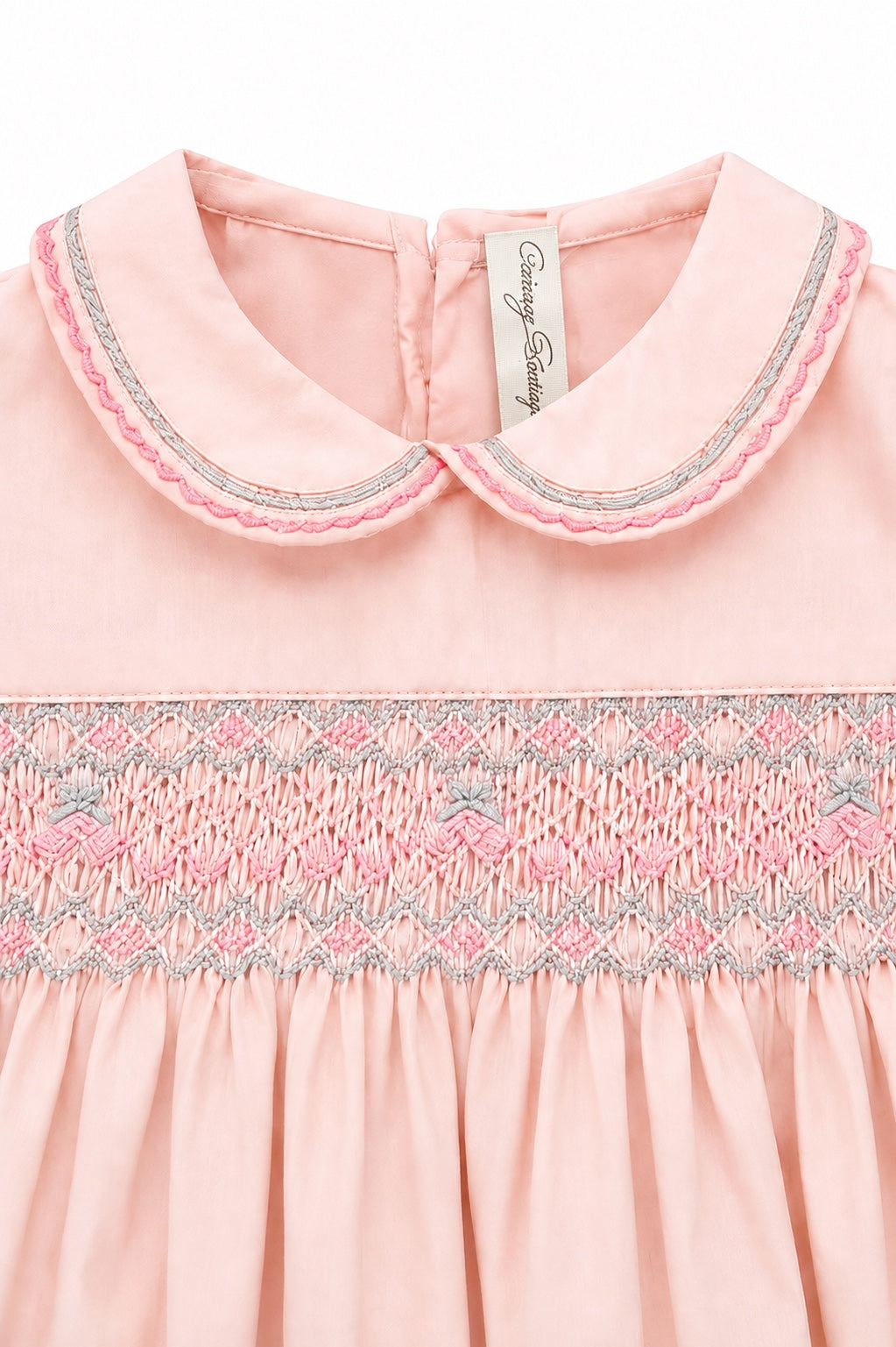 Carriage Boutique pink taffeta baby girl dress with a peter pan collar and intricate hand-smocked floral detailing.