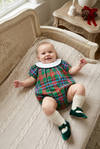 Carriage Boutique baby girl wearing a multicolor plaid bubble romper with a white collar, lying on a knit blanket.