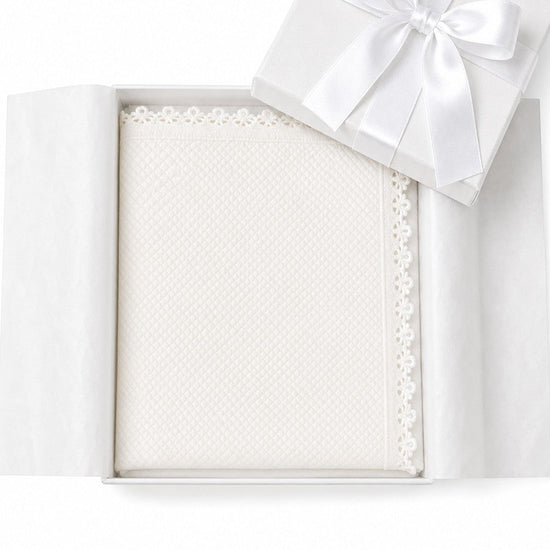 Carriage Boutique off-white quilted baby christening blanket with delicate lace trim inside a white gift box.
