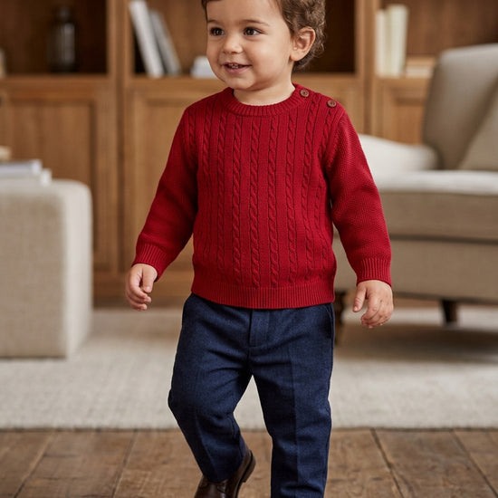 Carriage Boutique red cable knit crew neck sweater on a toddler boy wearing navy trousers and brown shoes