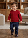 Carriage Boutique red cable knit crew neck sweater on a toddler boy wearing navy trousers and brown shoes