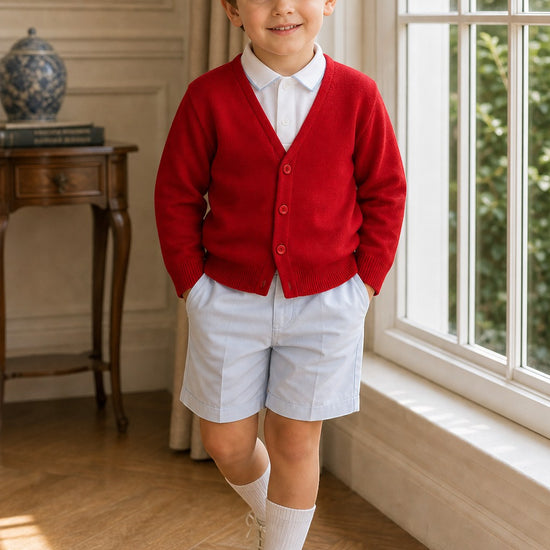 Carriage Boutique red cotton cashmere cardigan worn by a young boy with light blue shorts and white dress shoes