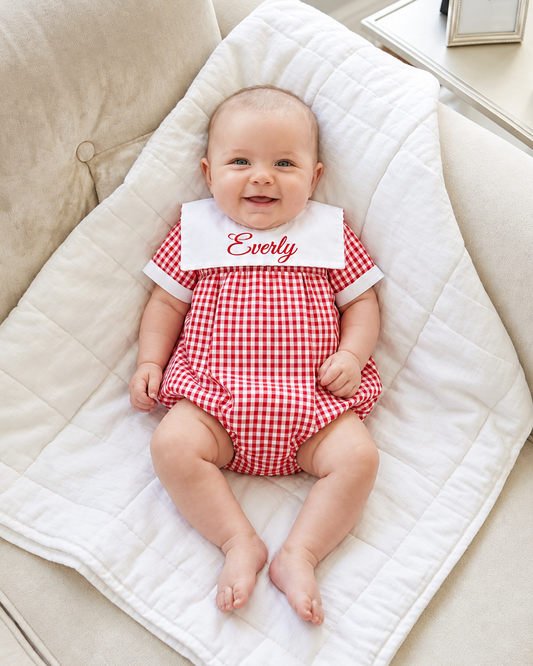Carriage Boutique red and white gingham check bib short romper with personalized monogram on a white baby blanket