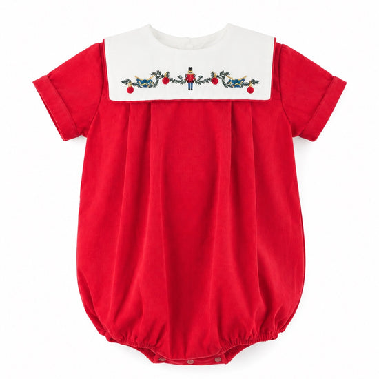 Carriage Boutique red cotton baby boy bubble romper with a white smocked bib featuring a festive nutcracker motif.