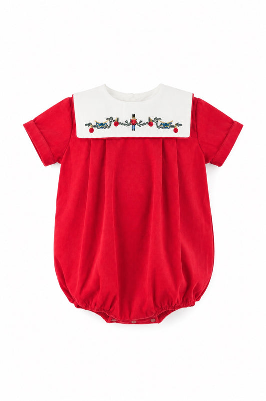 Carriage Boutique red cotton baby boy bubble romper with a white smocked bib featuring a festive nutcracker motif.