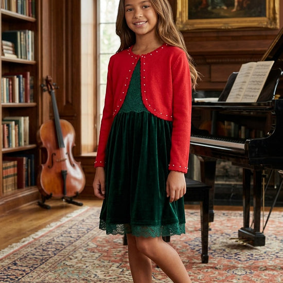 Carriage Boutique red bolero sweater with pearl accents worn by a girl over a green velvet dress in a library.