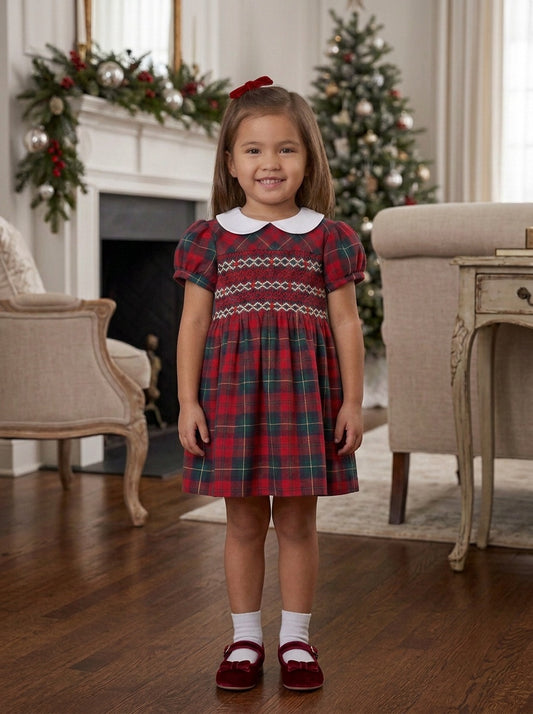 Carriage Boutique toddler girl wearing a red and green plaid dress with hand-smocked bodice and white Peter Pan collar