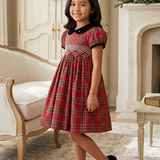 Carriage Boutique toddler girl wearing a red plaid cotton party dress with a black velvet collar and smocked yoke.