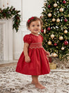 Carriage Boutique red taffeta baby dress with smocked diamond detailing and puffed sleeves near a Christmas tree