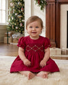 Carriage Boutique red silk baby dress with smocked floral detail and puffy sleeves worn by a toddler in a home setting