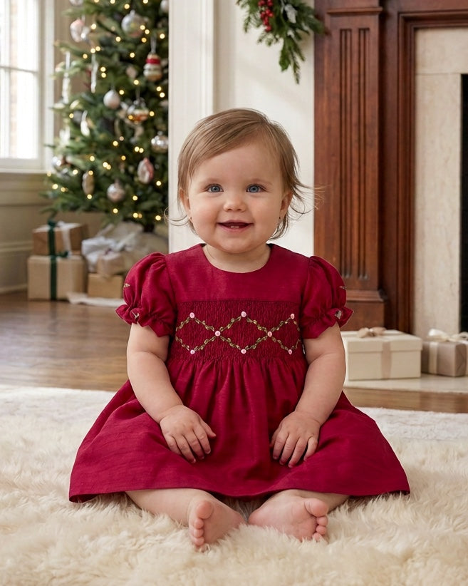 Carriage Boutique red silk baby dress with smocked floral detail and puffy sleeves worn by a toddler in a home setting