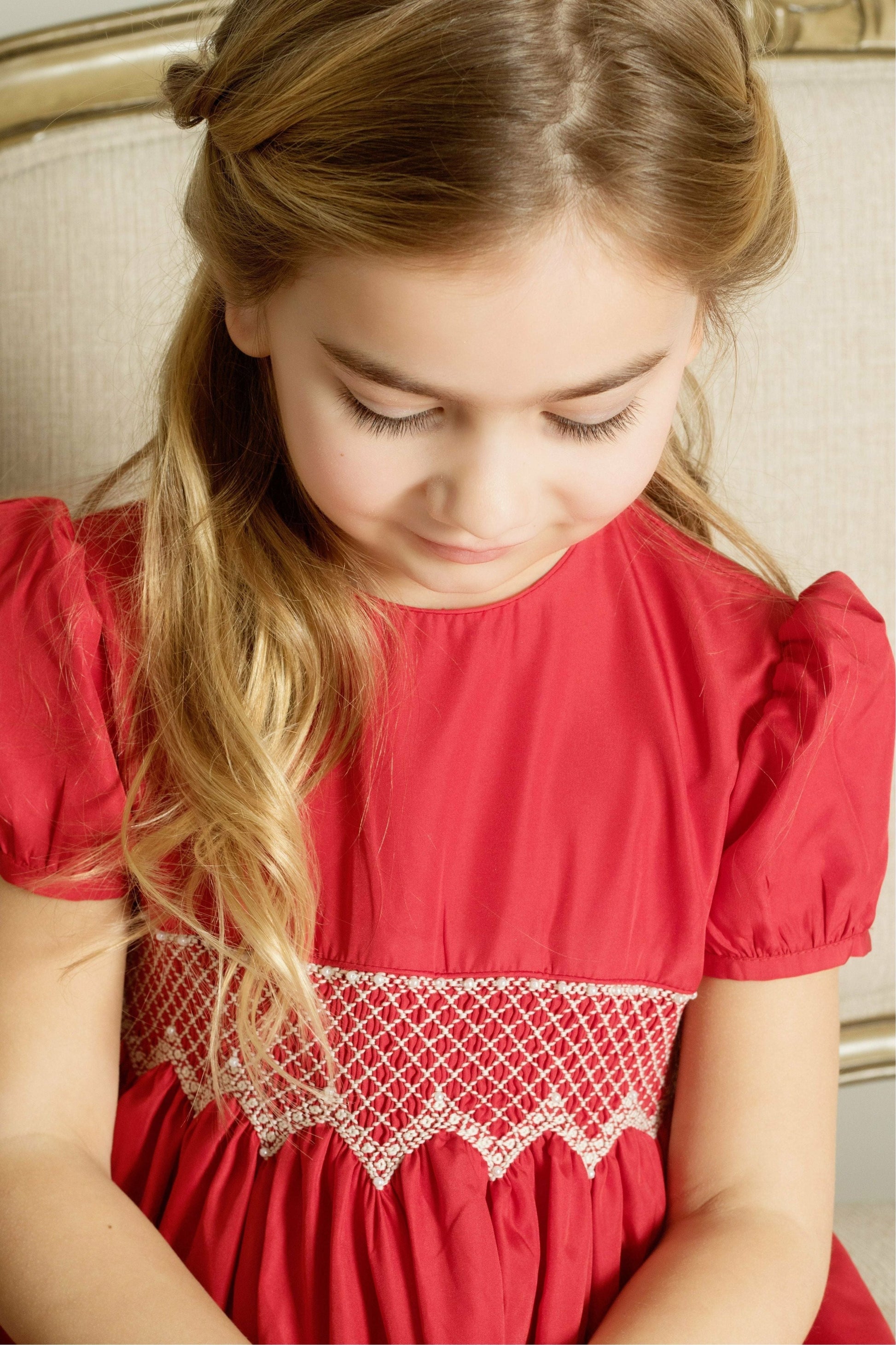 Carriage Boutique toddler girl in a red taffeta dress with smocked diamond detailing and puffed sleeves