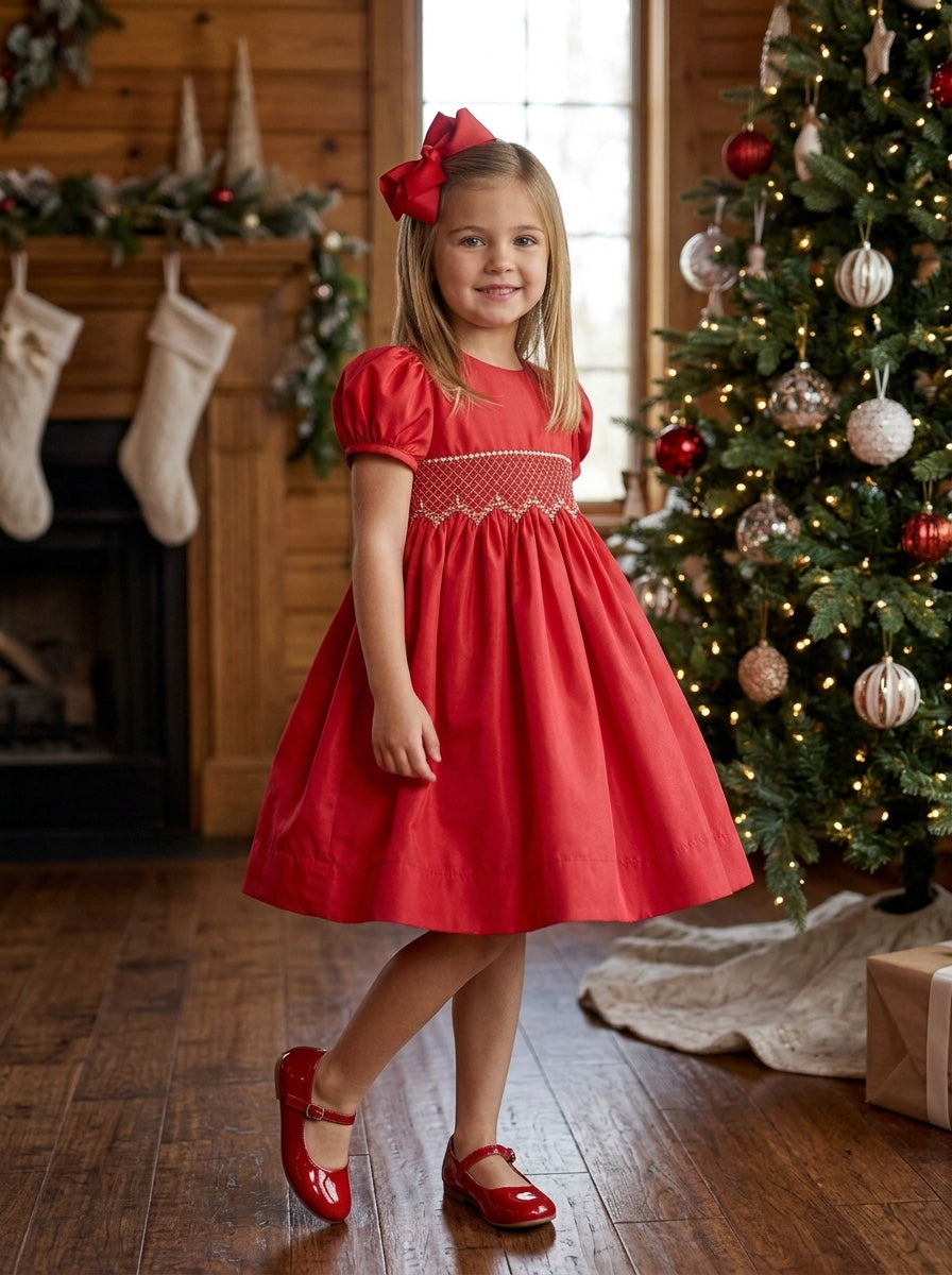 Carriage Boutique toddler girl in a red taffeta dress with smocked bodice, puffed sleeves, and matching hair bow.