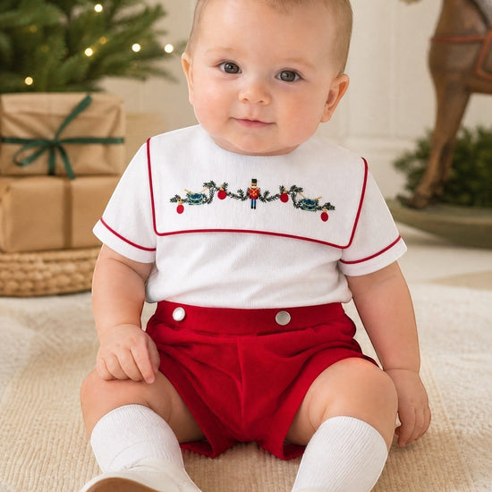 Carriage Boutique red wooden soldier smocked bib, white cotton shirt with red trim, and red shorts. Infant boy outfit.