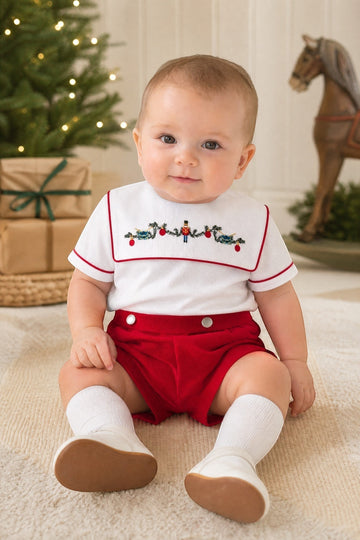Carriage Boutique red wooden soldier smocked bib, white cotton shirt with red trim, and red shorts. Infant boy outfit.