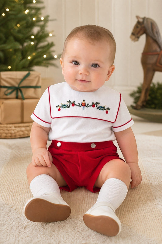 Carriage Boutique red wooden soldier smocked bib, white cotton shirt with red trim, and red shorts. Infant boy outfit.