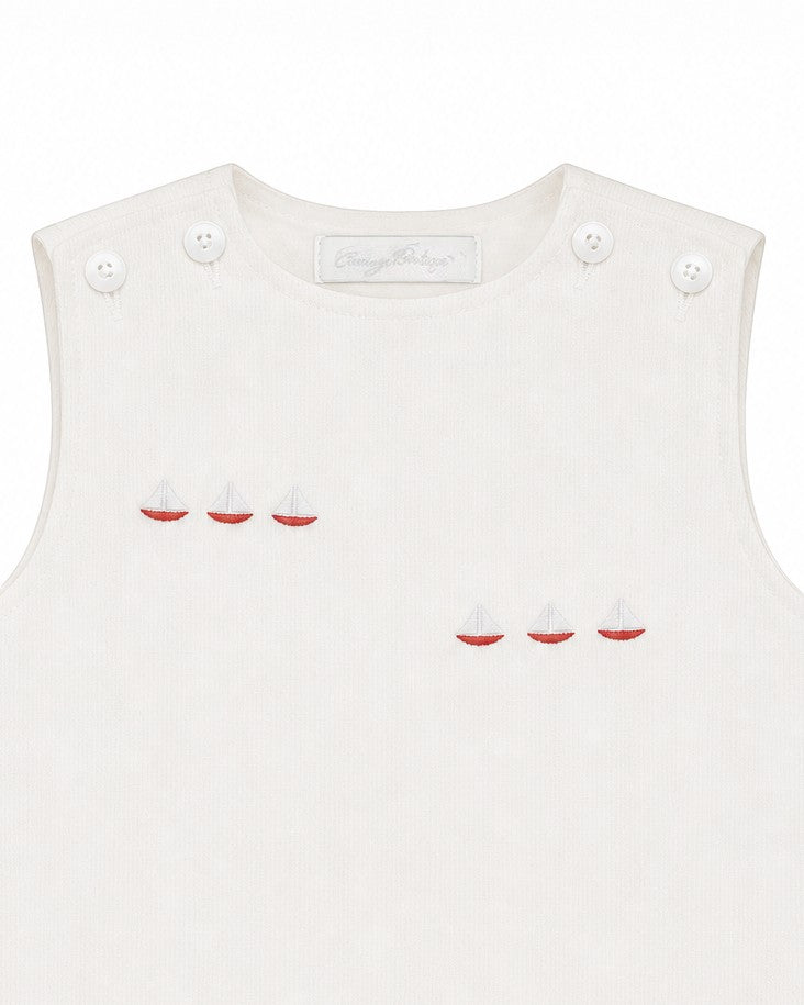 Carriage Boutique white sleeveless baby bubble with smocked detailing and embroidered red sailboats. Button closure.