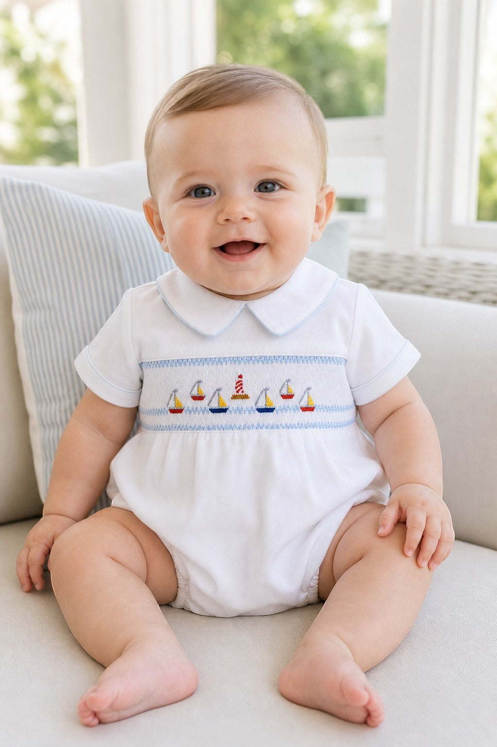 Carriage Boutique white bubble romper with smocked chest featuring sailboats and lighthouse, Peter Pan collar with blue piping.