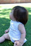 Carriage Boutique white sleeveless bubble with smocked detailing and embroidered red sailboats. Baby sitting on grass.