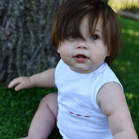 Carriage Boutique white sleeveless baby bubble with smocked detailing and embroidered red sailboats.
