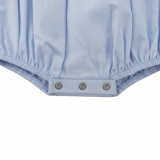 Carriage Boutique light blue smocked bubble romper with Peter Pan collar and train motif. Short sleeves, button back.