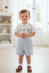Carriage Boutique toddler boy wearing a white and light blue smocked bobby suit with carousel horse embroidery
