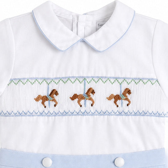 Carriage Boutique white baby bobby suit with blue trim and carousel horse smocking detail on the chest