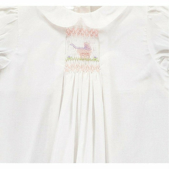 Carriage Boutique white baby dress with hand-smocked bodice, pastel pram embroidery, and Peter Pan collar.